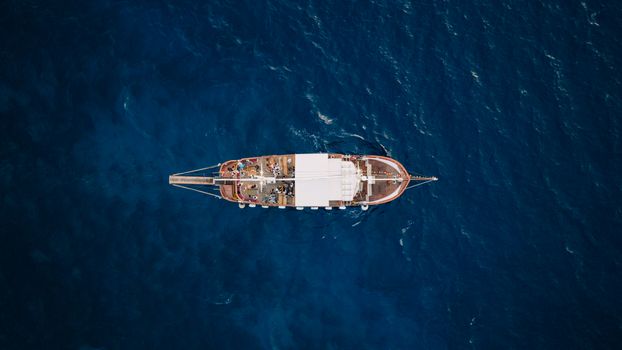 Aerial view of a cruise ship crossing deep blue sea at golden hour